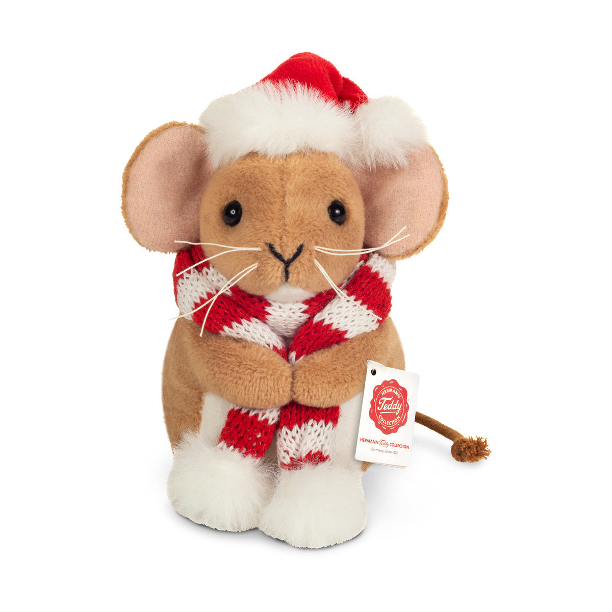 Das ist eine kleine Weihnachtsmaus mit Schal von Teddy-Hermann. Sie sitzt, ihr kurzes, dichtes Fell ist beige mit Schimmer, vorn am Bauch und auf den Füßen weiß und flauschig. Die Schnauze ist beige mit langen weißen Schnurrhaaren, die Ohreninnenseiten blassrosa, die Augen schwarz, die Nase schwarz und V-förmig. Der dünne braune Schwanz endet in einem Knoten. Sie trägt eine rote Weihnachtsmütze mit weißem Flauschrand; der Strickschal ist rot-weiß gestreift mit weißen Bommeln.