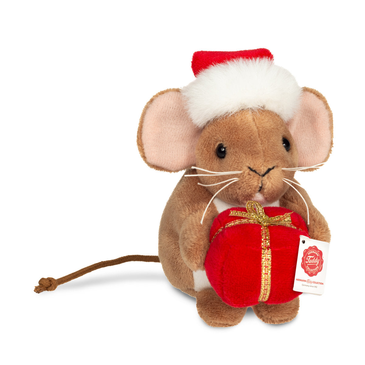 Das ist eine kleine Weihnachtsmaus von Teddy-Hermann. Sie sitzt aufrecht und hält ein rotes Geschenk mit goldenem Band. Das Fell ist braun, kurz und glatt, der Bauch weiß, die Ohreninnenseiten rosa. Die Augen sind schwarz und rund, die Nase ist schwarz, klein und dreieckig, die Schnurrhaare sind lang und weiß. Die Ohren sind groß und rund, der Schwanz ist lang und dünn. Dazu trägt sie eine rote Weihnachtsmütze mit weißem Plüschrand und Bommel. Der Ausdruck wirkt sanft und fröhlich.