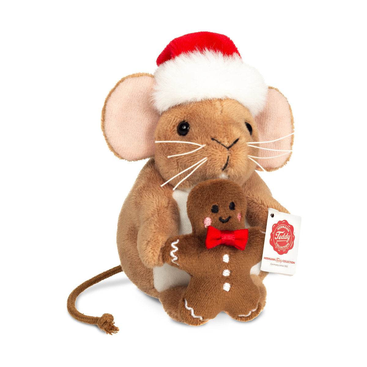 Das ist eine kleine Weihnachtsmaus mit Lebkuchenmann von Teddy-Hermann. Sie sitzt, hat kurzes braunes Fell, einen weißen Bauchfleck und einen langen dünnen Schwanz mit Knoten. Schnauze und Pfoten braun, Ohreninnenseiten blassrosa. Schwarze runde Augen, kleine schwarze Nase, weiße Schnurrhaare aus Faden. Sie trägt eine rote Weihnachtsmütze mit weißem Rand und Bommel und hält einen Lebkuchenmann mit weißem Zuckerguss und roter Fliege. Der Blick wirkt sanft und neugierig.