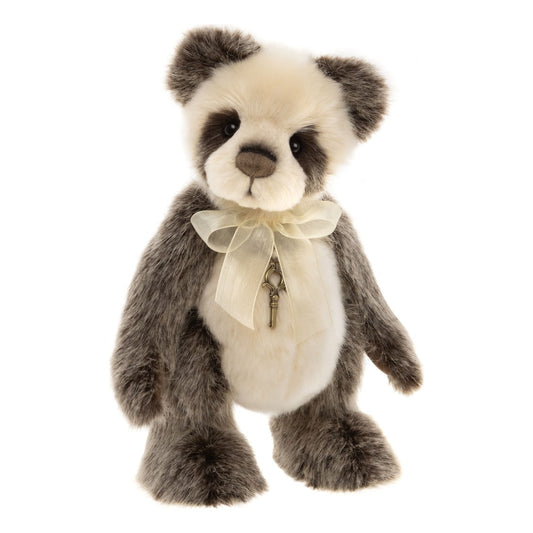 Das ist Ticklish, ein Teddy von Charlie Bears. Er sitzt allein, sein Fell ist lang und leicht zottelig mit sanftem Glanz, an Kopf und Bauch kürzer, an Armen, Beinen und Ohren flauschig. Stirn, Schnauze und Bauch sind weiß, Ohren, Arme, Beine und Augenpartie grau, Nase und Augenflecken braun. Pfotenballen dunkelbraun, Augen schwarz glänzend. Am Hals sitzt eine zarte beige Schleife, auf der Brust eine kleine Schlüsselkette. Der Ausdruck wirkt sanft und neugierig.