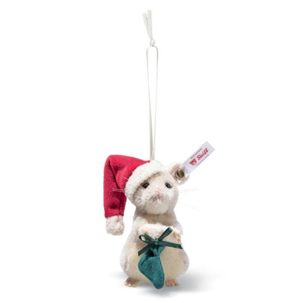 Das ist eine Weihnachtsmaus von Steiff. Das Mohairfell ist kurz, leicht gelockt und dicht, überwiegend weiß mit beigem Fleck am Bauch und zartem Rosa an Ohreninnenseiten und Pfotenspitzen. Sie sitzt aufrecht, ohne Gelenke, hält ein kleines grünes Söckchen und trägt eine rote Weihnachtsmütze mit weißem Rand. Die Augen sind schwarz und rund, die Nase ist klein, rosa und dreieckig, feine Schnurrhaare stehen von der Schnauze ab. Unten sind kleine beige Pfoten zu sehen.